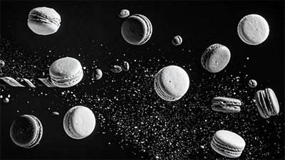 Photo noire et blanc representant des macarons (biscuits ronds) qui volent dans l'espace